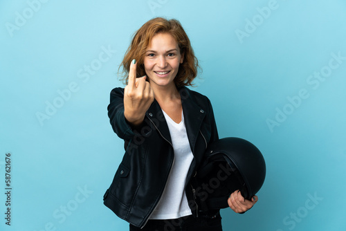 Georgian girl holding a motorcycle helmet isolated on blue background doing coming gesture