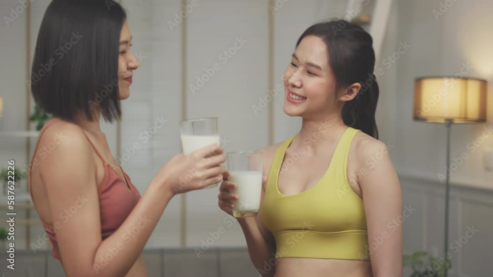 Attractive fitness asian woman finishing workout and drinking protein milk shake vitamins after training at home. Bodybuilding. Healthy lifestyle. Attractive fitness asian woman finishing workout and drinking protein milk shake vitamins after training at home. Bodybuilding. Healthy lifestyle.