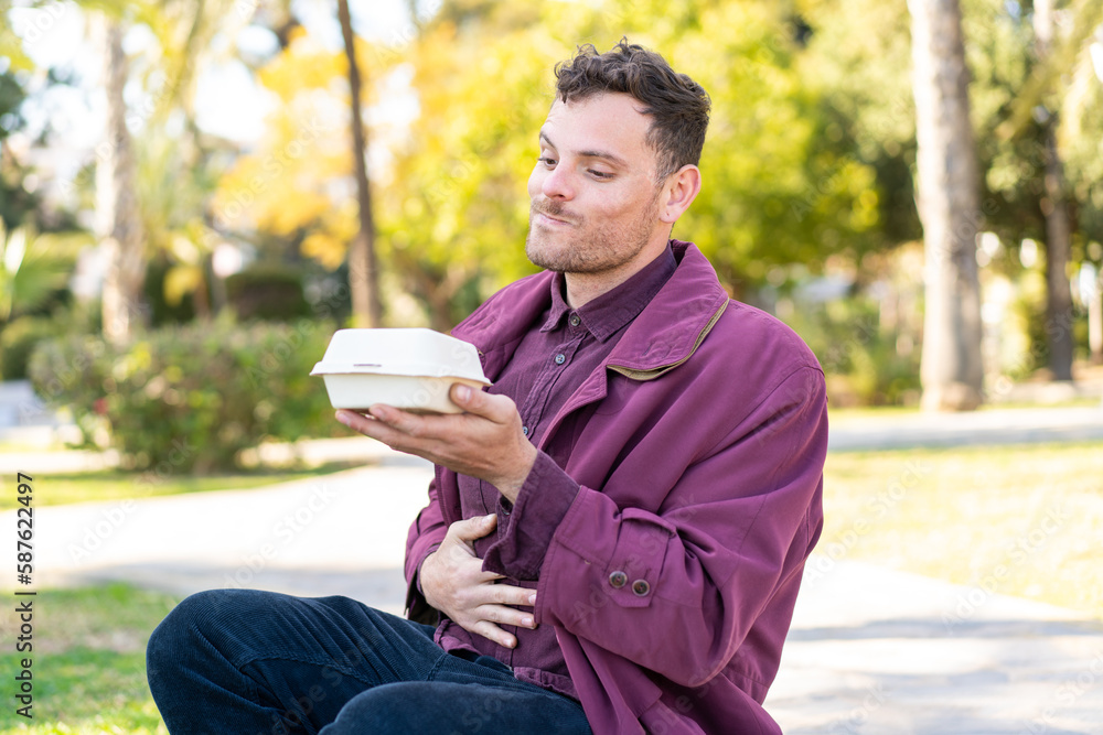 Young caucasian man at outdoors taking a box of takeaway food Young caucasian man at outdoors taking a box of takeaway food