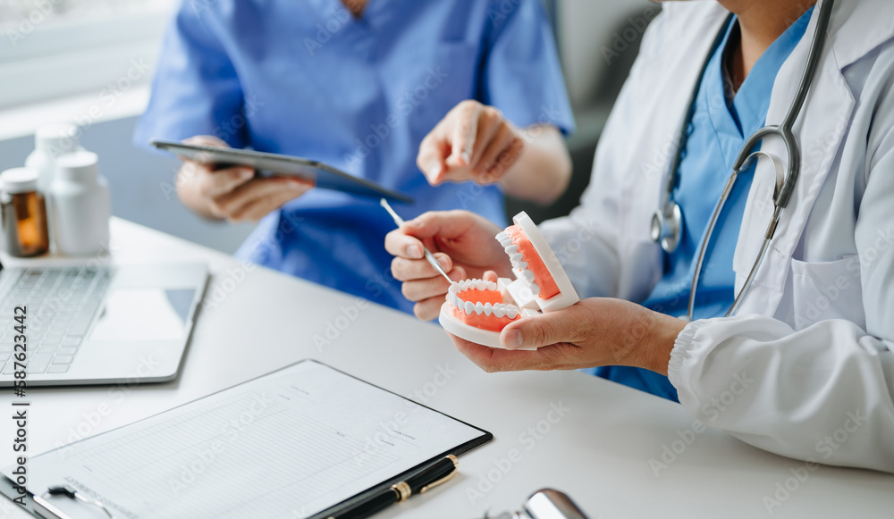 Dentist sitting at table with jaw samples tooth model and working with tablet and laptop in dental office professional dental clinic. medical doctor working. Dentist sitting at table with jaw samples tooth model and working with tablet and laptop in dental office professional dental clinic. medical doctor working.