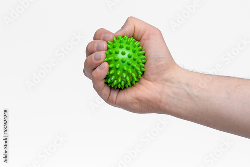 Zielona piłka z kolcami wciskana w dłoń jako forma rehabilitacji nadgarstka