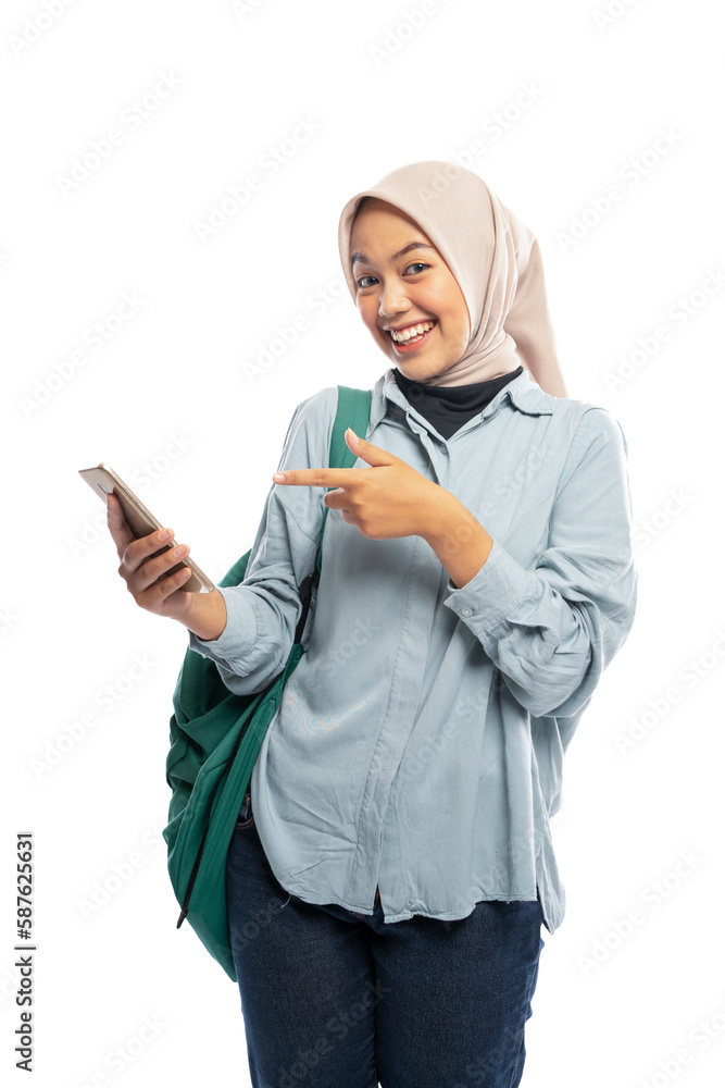 smiling Asian female hijab student pointing at cell phone on white background smiling Asian female hijab student pointing at cell phone on white background