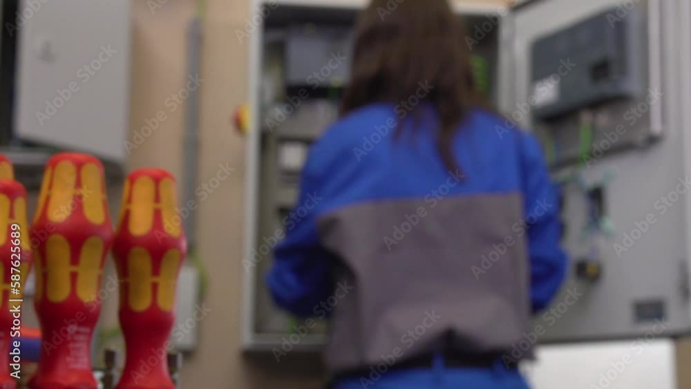 female electrician working with screw driver on switch cabinet female electrician working with screw driver on switch cabinet
