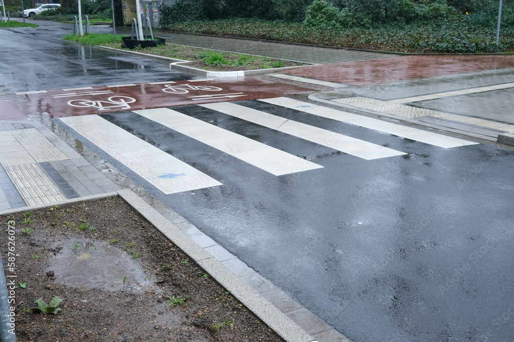 Fototapeta premium Bike path crosses car road in pouring rain