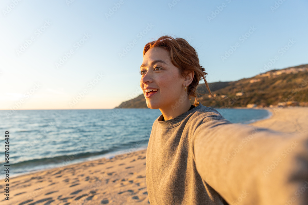 redhead woman taking a selfie on the beach redhead woman taking a selfie on the beach