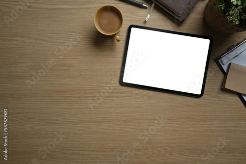 Flat lay, top view of simple workspace with digital tablet, cup of coffee and notebook on wooden table