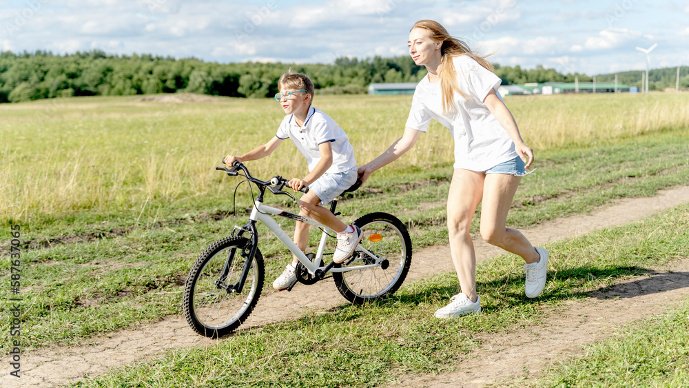 loving mother help her cute son ride a bicycle