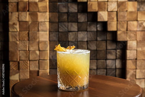 An iced fruity alcoholic cocktail in a lowball rocks glass garnished with dried pineapple