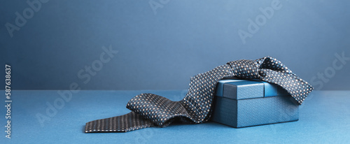 Happy Fathers Day background banner. Two blue gift boxes with ribbon bow and necktie on dark blue table. Monochrome. Gift delivery for him. Male fashion photo