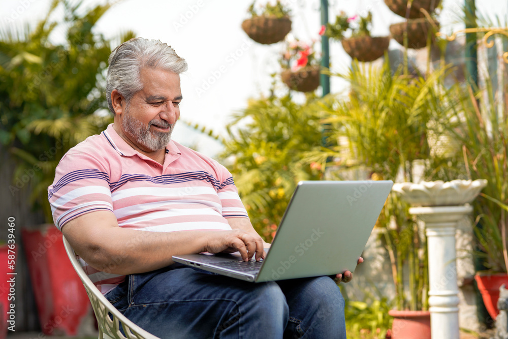 Indian old man using laptop at garden. Indian old man using laptop at garden.