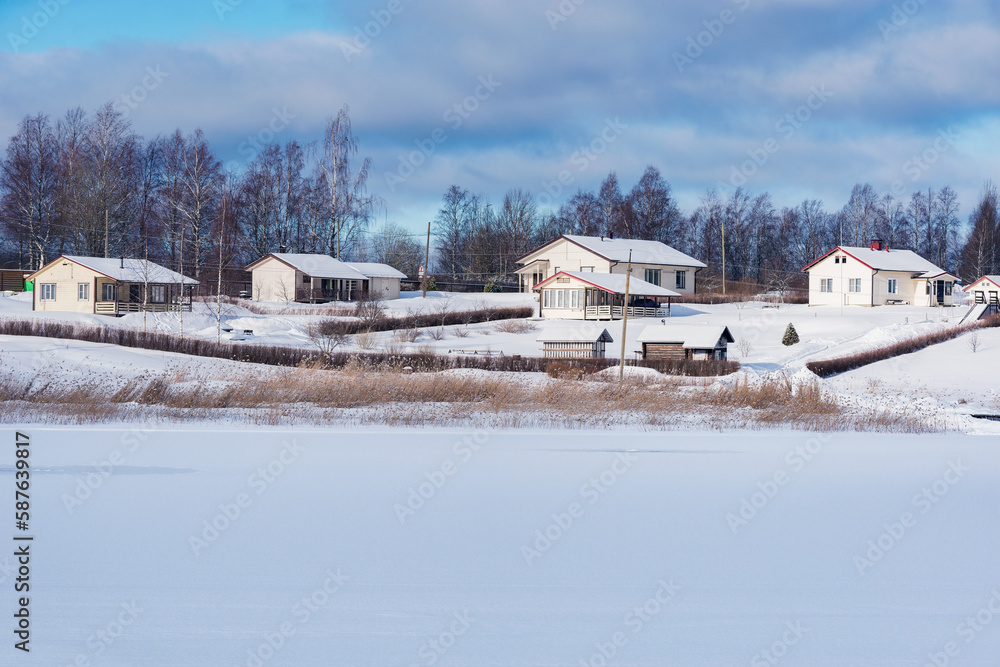 Cottages by the frozen river at winter morning.