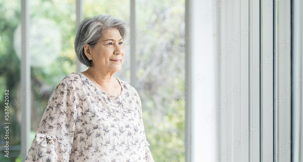Senior Asian woman standing alone near windows in hospital. Old Asian female using walking stick at home. Retirement, health care and ageing concept Senior Asian woman standing alone near windows in hospital. Old Asian female using walking stick at home. Retirement, health care and ageing concept