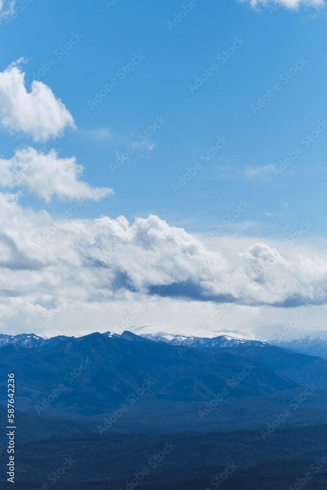 Landscape with mountain peaks in the distance in early spring. Beautiful view of the Caucasian Mountain range, nature reserve in Krasnodar Region and Republic of Adygea, Russia. Landscape with mountain peaks in the distance in early spring. Beautiful view of the Caucasian Mountain range, nature reserve in Krasnodar Region and Republic of Adygea, Russia.