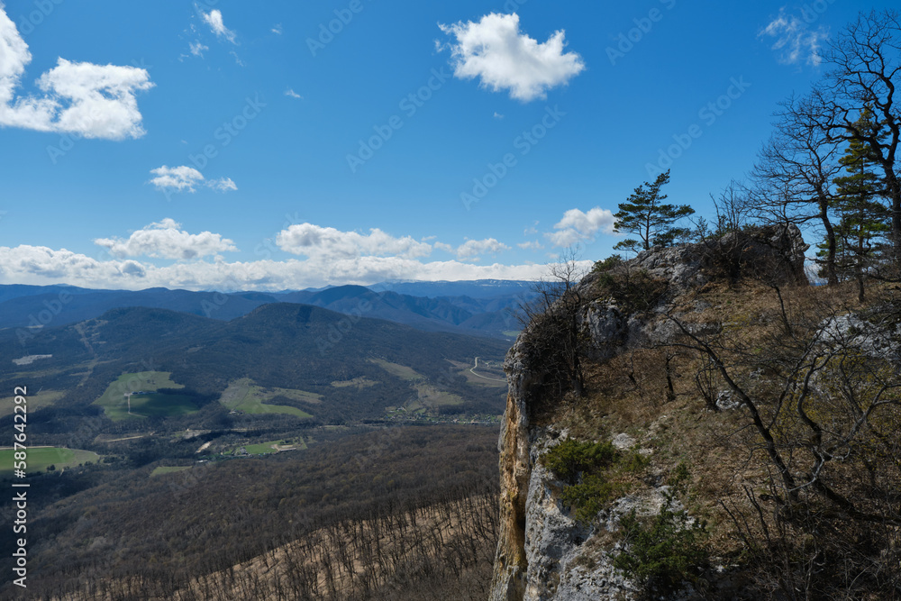 Landscape with mountain peaks in distance in early spring. View from top of cliff in village Dakhovskaya. Beautiful view Caucasian Mountain range, nature reserve in Republic Adygea, Russia. Landscape with mountain peaks in distance in early spring. View from top of cliff in village Dakhovskaya. Beautiful view Caucasian Mountain range, nature reserve in Republic Adygea, Russia.