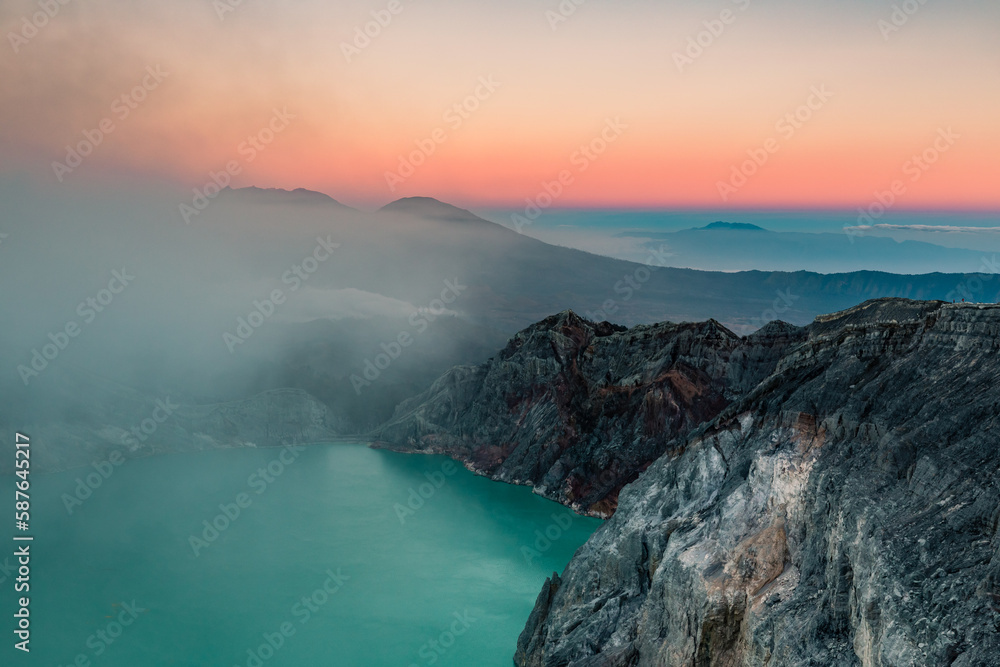 Sunrise over Kawah Ijen Volcano revealing acid turquoise lake and toxic sulfur gases and dead trees next to illegal mining operation, Java, Indonesia