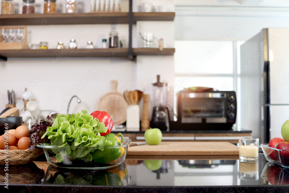 Colorful fresh vegetables salad in a glass cup and food ingredients on table counter kitchen with blurred background of beautiful modern kitchen, healthy natural food concept with copy space. Colorful fresh vegetables salad in a glass cup and food ingredients on table counter kitchen with blurred background of beautiful modern kitchen, healthy natural food concept with copy space.