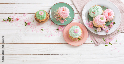 pink and green cupcakes with spring flowers on white wooden background