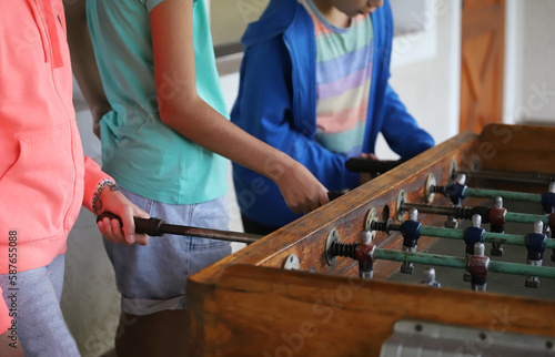 Children playing metegol. Foosball. Soccer hall game. Traditional game. Soccer game. Table with soccer players. Old wooden foosball. Football players. Dolls with blue and red painted T-shirts. photo