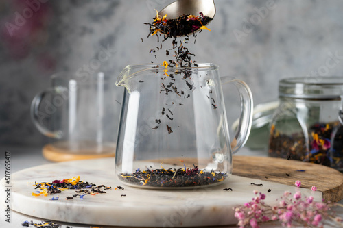 Obraz na płótnie Adding loose black leaf tea to glass tea pot. Making tea.