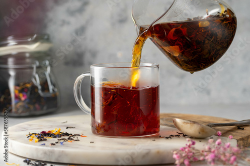 Pouring freshly brewed black loose leaf tea in glass cup. Lifestyle drinking tea. photo