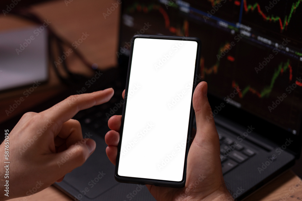 Closeup of trader hand holding smartphone using mobile app touching screen with mockup working online, selective focus. Technology, online trading concept Closeup of trader hand holding smartphone using mobile app touching screen with mockup working online, selective focus. Technology, online trading concept