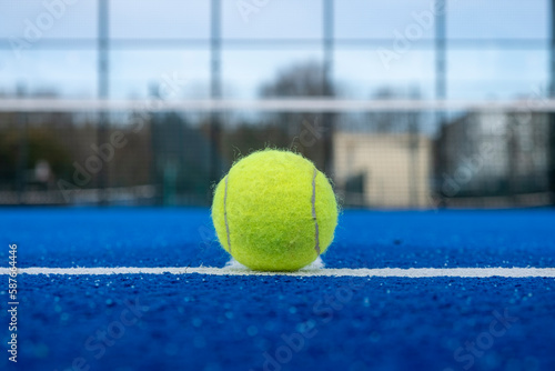 view of a ball on the baseline of a blue paddle tennis court © Vic