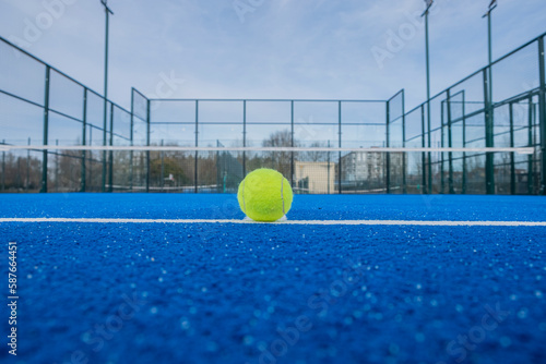 view of a ball on the baseline of a blue paddle tennis court, racket sport concept © Vic
