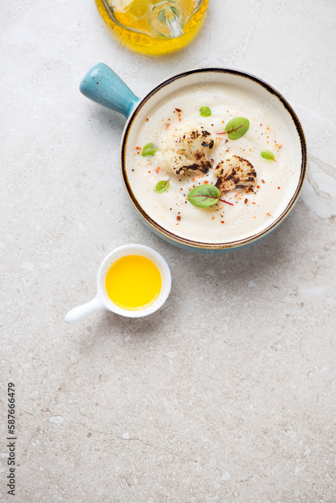 Cauliflower cream-soup in a turquoise serving bowl, vertical shot on a beige stone background, high angle view, copy space Cauliflower cream-soup in a turquoise serving bowl, vertical shot on a beige stone background, high angle view, copy space