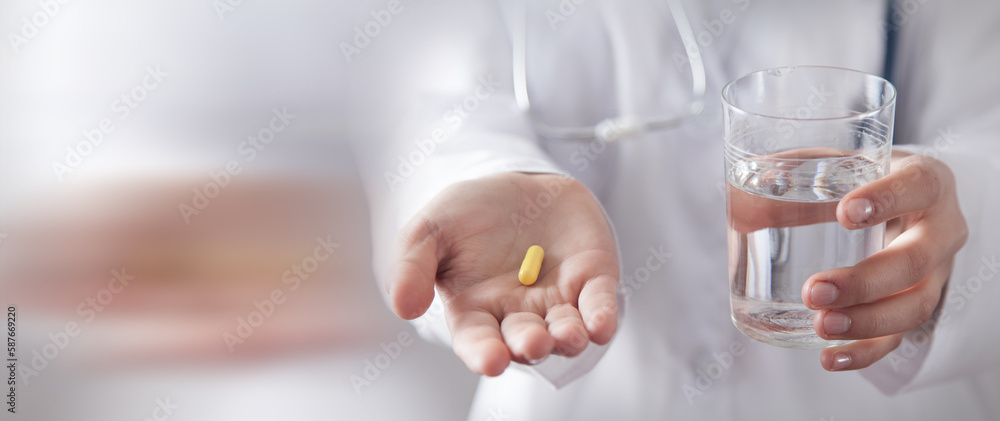 Doctor holding pill and a glass of water. Doctor holding pill and a glass of water.