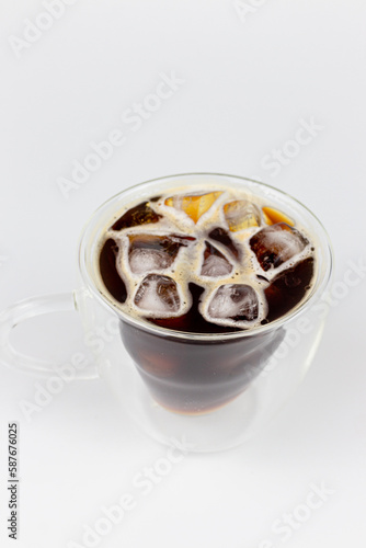 Cup of coffee with ice cubes and lemon on white background.