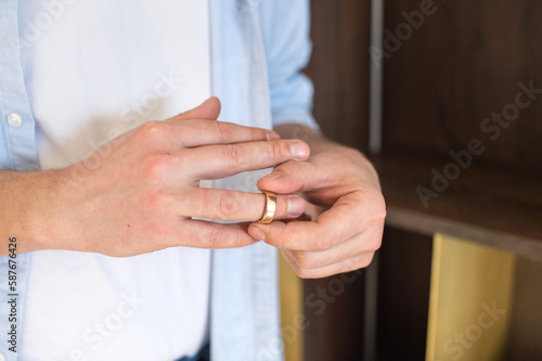 A business man removes a gold wedding ring from his right hand