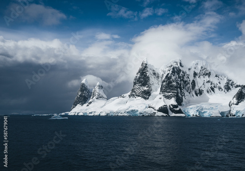 Landscape of snowy mountains and icy shores of the Lemaire Channel in the Antarctic Peninsula, Antarctica. Global warming and climate change concept. photo