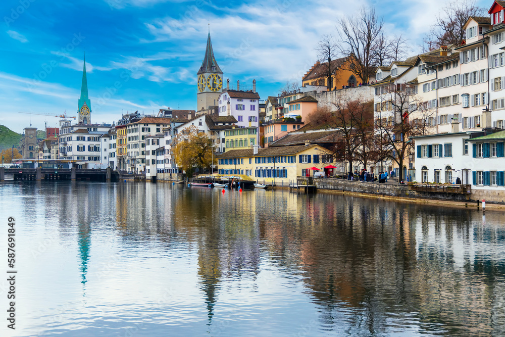 Obraz premium Cityscape or beautiful landscape of Zurich's old town in winter blue sky.People walk along Limmat river.Clock tower with cloud.Vintage city in Europe.River with reflection.Panorama style.