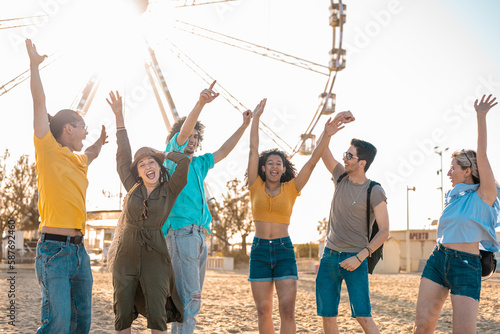 Group of friends having a party on the beach, ferris wheel on background