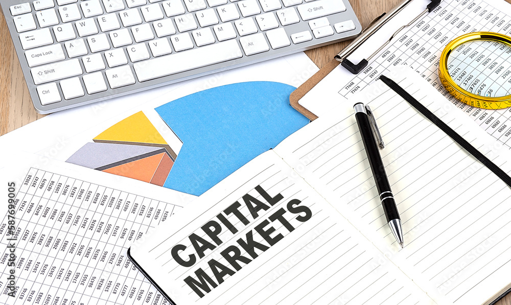 Fototapeta premium CAPITAL MARKETS text on a paper on chart background