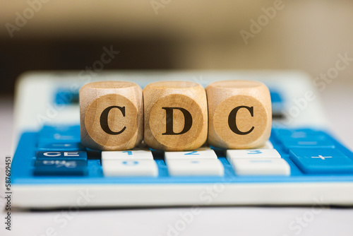 A sigla CDC para Código de Defesa do Consumidor em Português do Brasil escrita em dados de madeira que estão sobre uma calculadora azul. photo