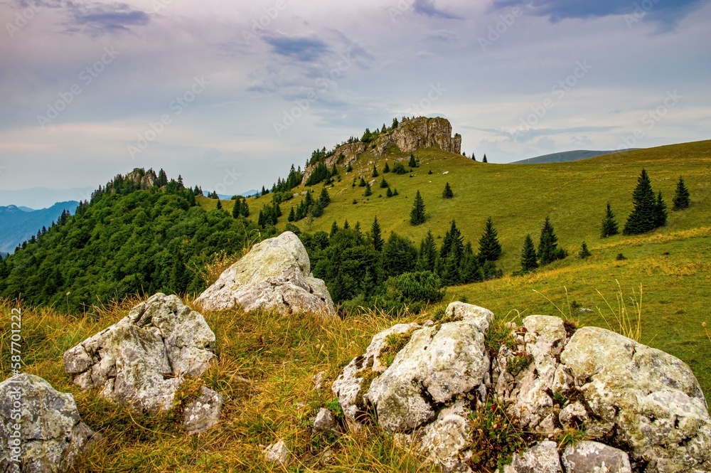 Mountain landscape with beautiful colorful sky, rocky cliff and mountain meadows with trees.Rock in Fatras with pasture