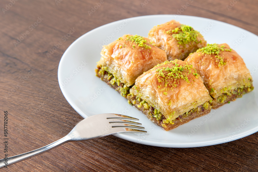 Turkish baklava with pistachio in plate.A plate baklava on wooden background,top view
Turkish baklava with pistachio in plate.A plate baklava on wooden background,top view