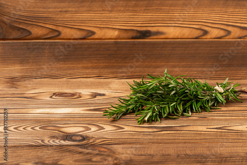 Rosemary on brown texture wooden background. Fresh spice herbs. Seasoning for meat and fish. Recipe. Organic bouquet of fresh rosemary on the table. Place for text. Place to copy.