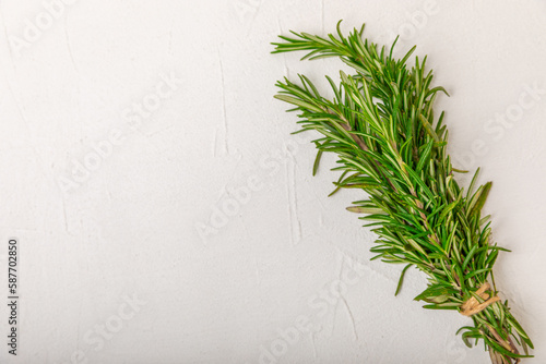 Rosemary on a white textured wooden background. Fresh spice herbs. Seasoning for meat and fish. Recipe. Organic bouquet of fresh rosemary on the table. Place for text. Place to copy.