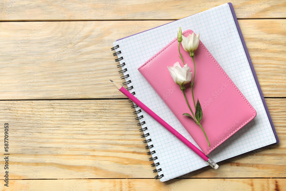 notebooks and pencils beautiful eustoma flowers on a natural wooden table. top view notebooks and pencils beautiful eustoma flowers on a natural wooden table. top view