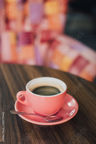 Pink cup of black coffee on a table in a cafe.