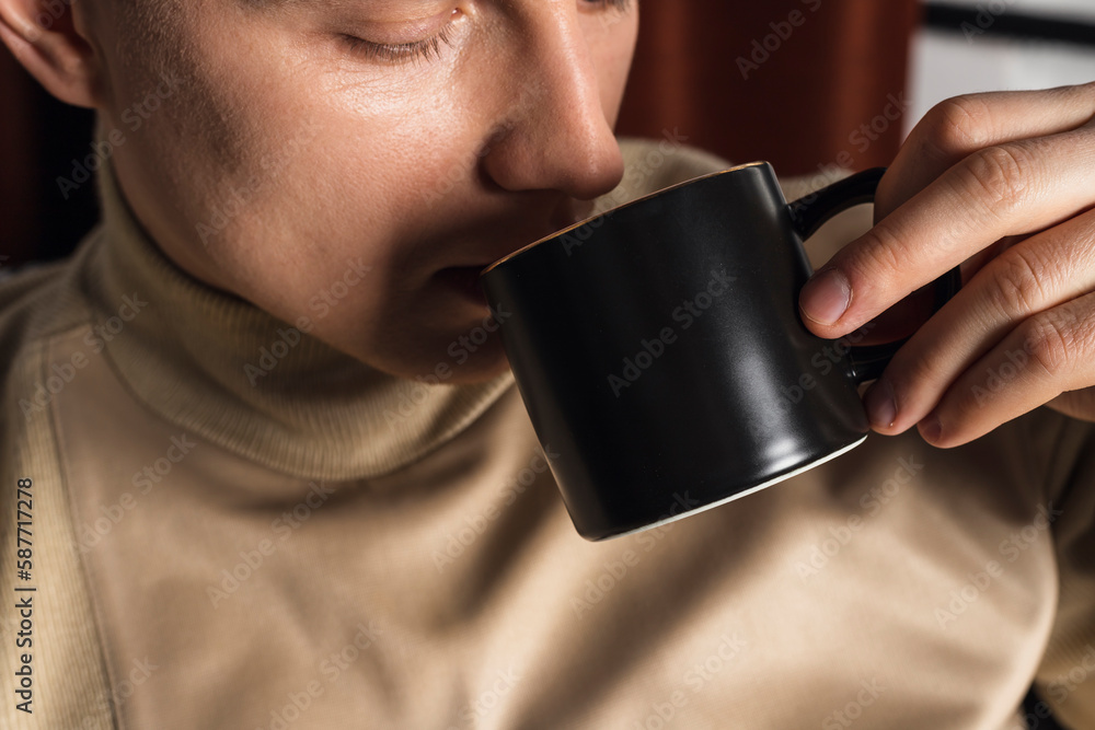 Attractive happy smart young man sitting on a floor in the living room, using phone, drinking coffee Attractive happy smart young man sitting on a floor in the living room, using phone, drinking coffee