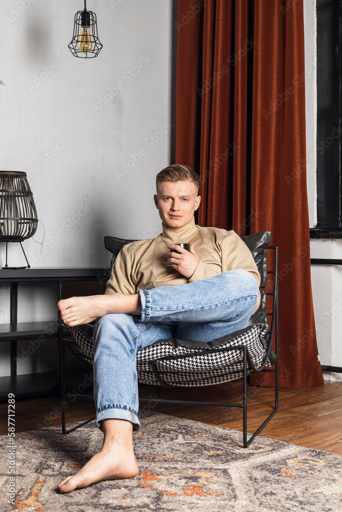 Lazy morning. Successful millennial man relaxing on comfy sofa at home after finishing work looking aside with glad smile. Calm young guy taking pleasure in awaited weekend enjoying peaceful dreams