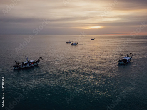 fishing boats in the middle of the sea fishing for clams at dawn