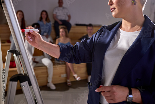 Cropped speaker giving presentation to students in hall at university.conference hall. People sit listening while speaker is writing on board. Scientific, business event, training. Education