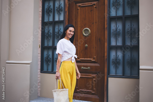 Half length portrait of cheerful female tourist smiling at camera during free leisure time for exploring beautiful town, happy Caucaisan woman in yellow skirt posing and rejoicing outdoors