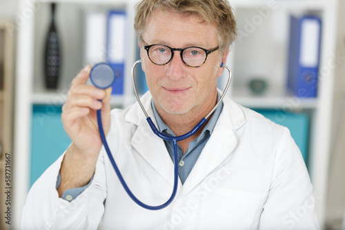 funny male doctor wearing glasses and sthetoscope smiling to camera photo