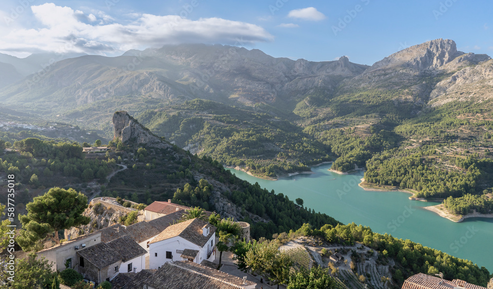 Views areas of the Guadalest reservoir with crystal clear turquoise waters between mountains with some houses nearby. Alicante. Spain