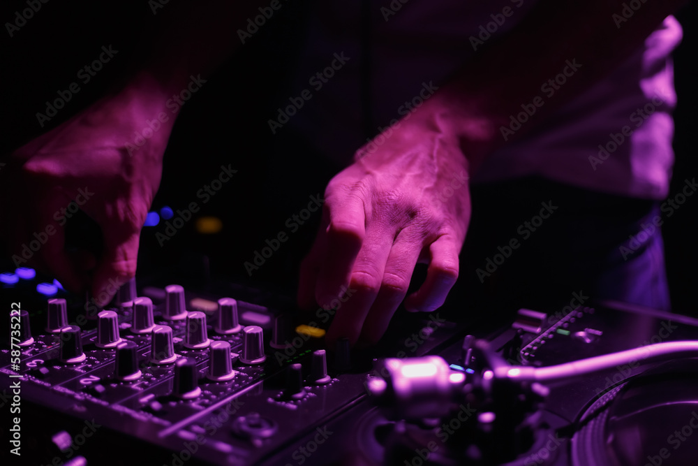 Hip hop DJ mixing music in dark night club. Hands of disc jockey playing set on stage Hip hop DJ mixing music in dark night club. Hands of disc jockey playing set on stage